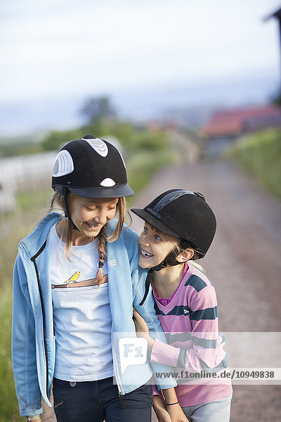 Two sisters wearing horseback riding caps