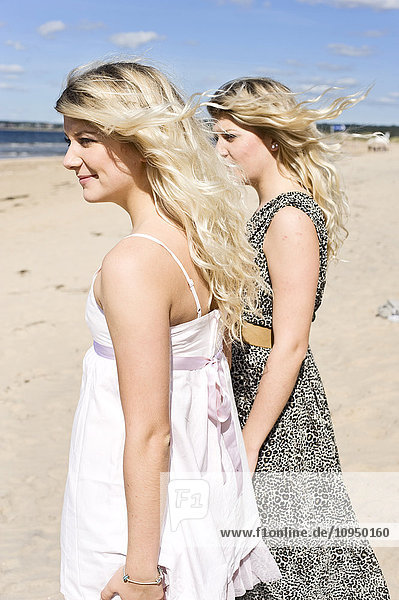 Junge Frauen stehen am Strand und schauen aufs Meer