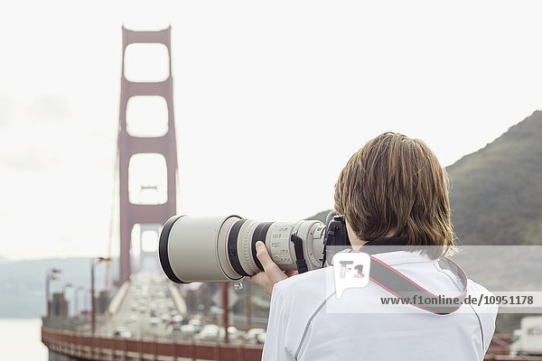 Junge beim Fotografieren  Golden Gate Bridge im Hintergrund
