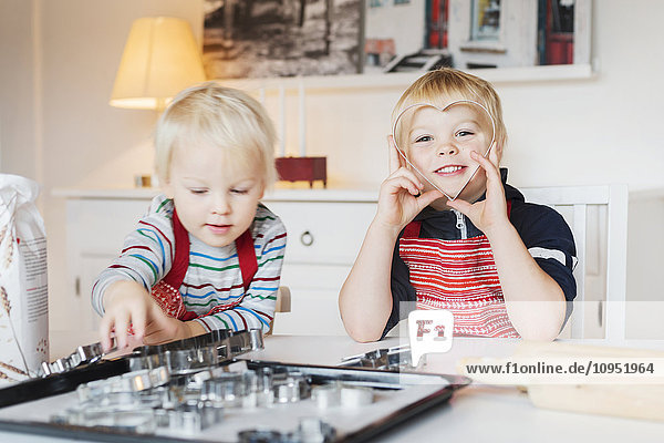 Two boys playing with cookie cutters at home