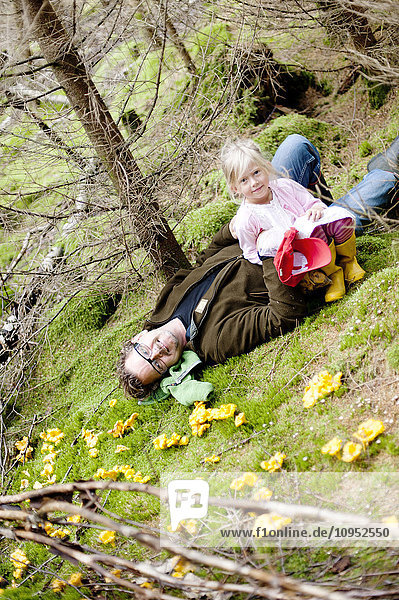 Mädchen mit Vater auf Moos im Wald