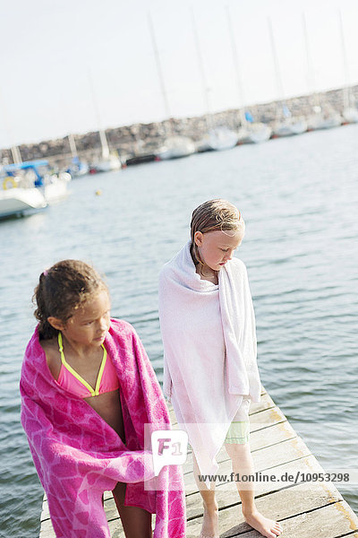 In Handtücher eingewickelte Mädchen stehen auf dem Pier