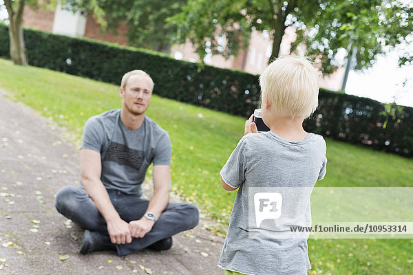 Sohn fotografiert seinen Vater im Park