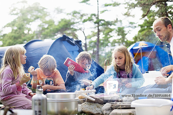 A family eating food outside a tent  Sweden.