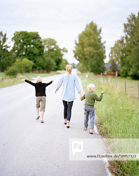 Mutter mit ihren beiden Söhnen beim Spaziergang auf einer Straße  Schweden.