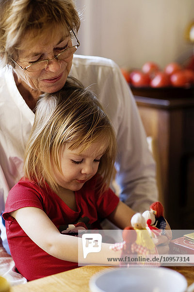 A grandmother playing with her granddaughter in the kitchen  France.