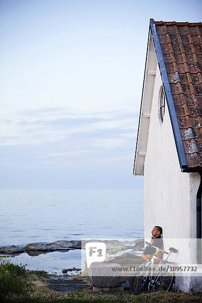 Mann mit Fahrrad vor einem Haus  Schweden.