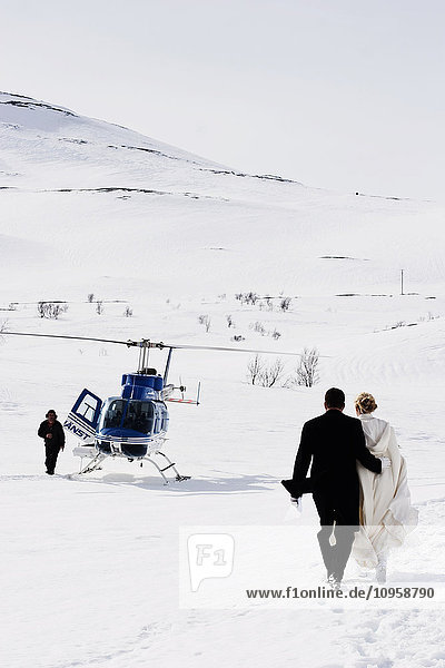 Bridal couple walking towards a waiting helicopter  Sweden.