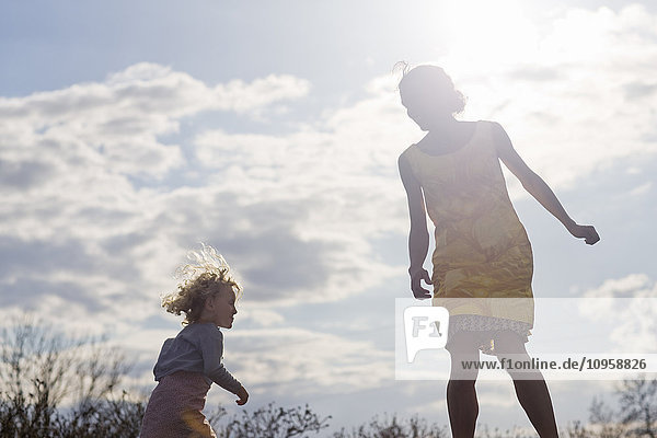 Mother and daughter jumping against the light  Sweden.