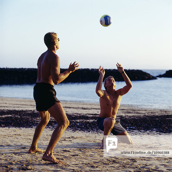 Two men playing volleyball on beach