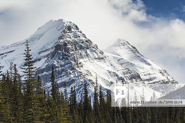 Nahaufnahme von zwei schneebedeckten Berggipfeln mit Wolkendecke und etwas blauem Himmel; Banff  Alberta  Kanada'.
