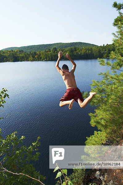 Junge  der von einer Klippe in den See springt; Lac des Neiges  Quebec  Kanada'.
