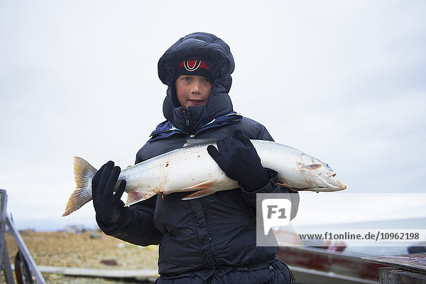 Junge hält frisch gefangenen Seesaibling am Ufer  in der Nähe von Cambridge Bay; Nunavut  Kanada