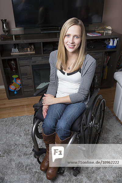 Junge behinderte Frau in einem Rollstuhl in ihrem Wohnzimmer; Spruce Grove  Alberta  Kanada
