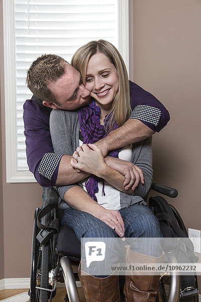 Ehemann umarmt seine behinderte Frau in ihrem Haus; Spruce Grove  Alberta  Kanada'.