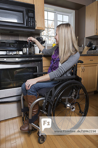 Junge behinderte Frau beim Kochen in ihrer Küche; Spruce Grove  Alberta  Kanada'.