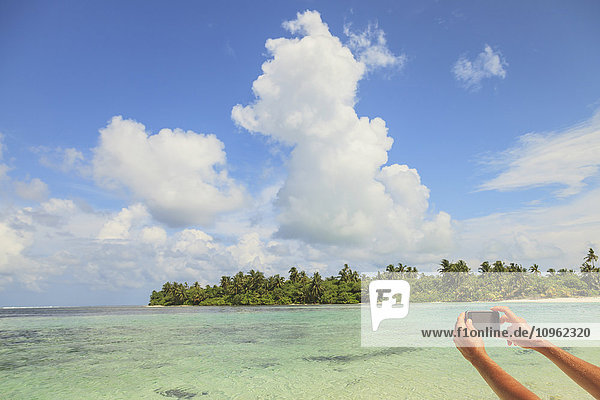 Frau fotografiert ein Atoll mit einem Smartphone; Insel Medahutthaa  Nord-Huvadhoo-Atoll  südliche Malediven'.