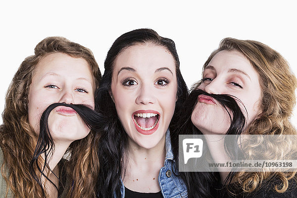 Drei junge Frauen in humorvoller Pose mit langen Haaren als Schnurrbart; Alberta  Kanada