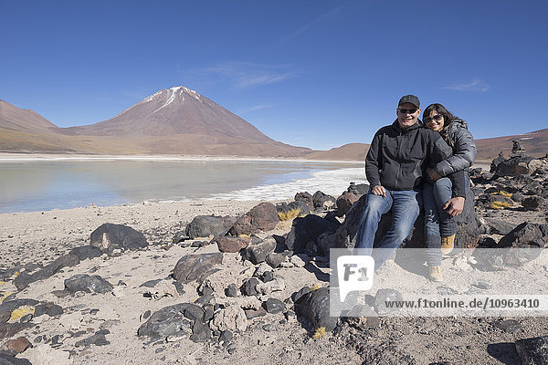 'Couple sitting on the shores of Laguna Verde  a salt lake on the Chilean border; Bolivia'