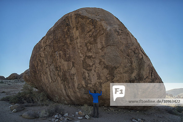 'Person standing under a large boulder in Richtersveld National Park; South Africa'
