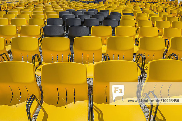 Schwarze Stühle zwischen gelben Plastikstühlen in Reihen; Locarno  Tessin  Schweiz'.