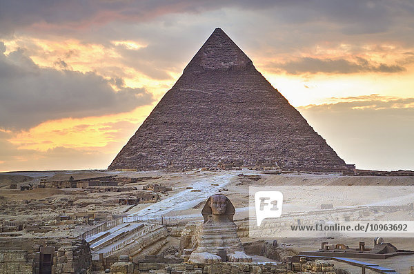 Sonnenuntergang  Sphinx (Vordergrund)  Chephren-Pyramide (Hintergrund)  Die Pyramiden von Gizeh; Gizeh  Ägypten'.