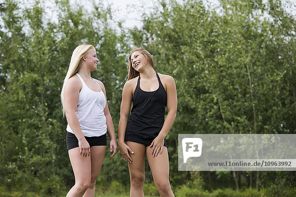 Zwei Freundinnen im Teenageralter  die zusammen in einem Park spazieren gehen und sich unterhalten; Edmonton  Alberta  Kanada'.