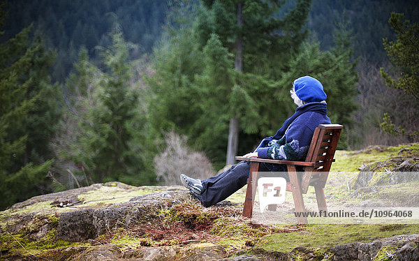 Frau sitzt auf einem Stuhl und betrachtet die Natur; Bowen Island  British Columbia  Kanada'.