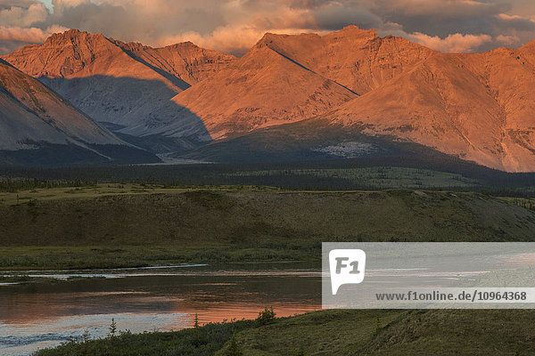 Die Mitternachtssonne scheint auf die Berge  die den Wind River im Peel-Wassereinzugsgebiet säumen; Yukon  Kanada .