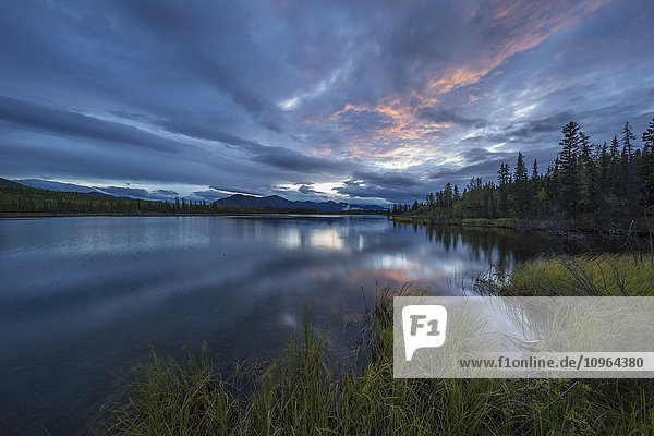 Sonnenuntergang beleuchtet ein Wolkenband über dem Jackfish Lake; Yukon  Kanada'.