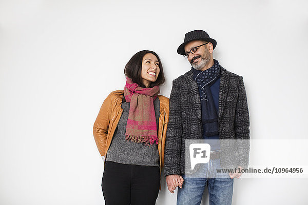 'Persian man and tibetan woman leaning against a wall smiling and holding hands; Toronto  Ontario  Canada'