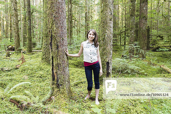Porträt eines Mädchens im Teenageralter  das sich an einen Baum im Wald lehnt; Chilliwack  British Columbia  Kanada'.