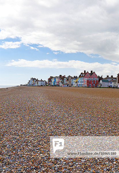 Leerer Strand mit bunten Ferienhäusern in der Ferne; Aldeburgh  Suffolk  England'.