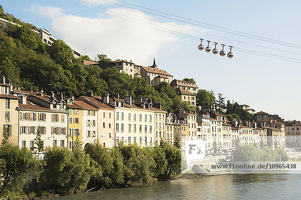 Blasengondel  die über alte Gebäude entlang eines Flusses fährt; Grenoble  Frankreich'.