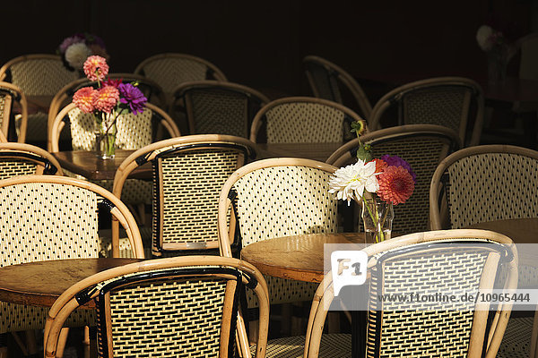 Ein Blumenstrauß zwischen leeren Stühlen und Tischen eines Pariser Bistros; Paris  Frankreich'.