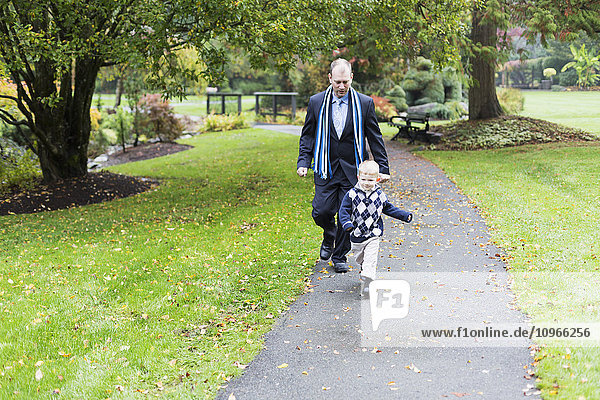 Ein Vater und sein Sohn gehen auf einem Weg in einem Park; Surrey  British Columbia  Kanada'.