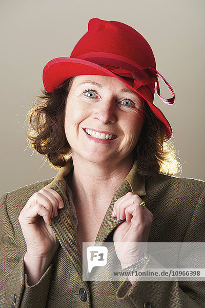 'Portrait of a woman with brunette hair wearing a red hat holding jacket lapels; Caldecott  England'