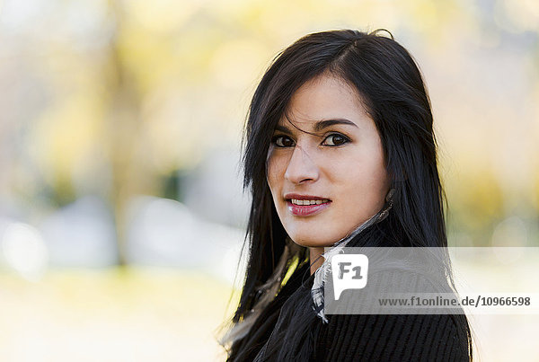 'A young aboriginal female model smiles and looks at the camera in a shoulders up headshot taken in the outdoors in autumn; Vancouver  British Columbia  Canada'