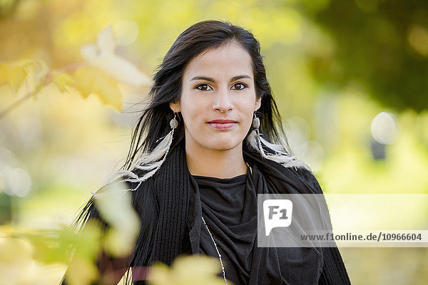'A young aboriginal female model looks at the camera in a shoulders up headshot taken in the outdoors in Autumn; Vancouver  British Columbia  Canada'