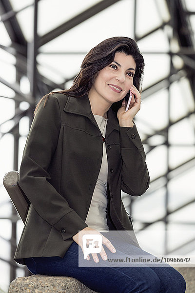 Ältere Geschäftsfrau  die in einer Pause im Atrium eines Bürogebäudes mit ihrem Handy telefoniert; Edmonton  Alberta  Kanada'.
