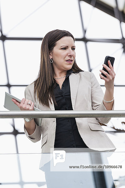 Ältere Geschäftsfrau schockiert über eine auf ihrem Smartphone empfangene Nachricht; Edmonton  Alberta  Kanada .