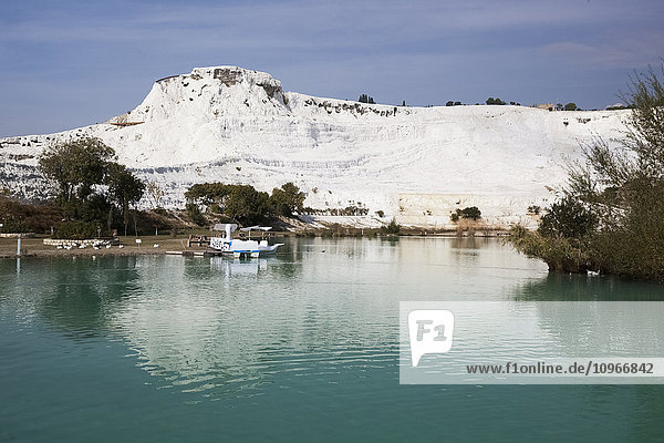 Türkisfarbenes Wasser in einem Pool  in dem sich eine weiße Wand aus Mineralienablagerungen spiegelt; Pamukkale  Türkei'.