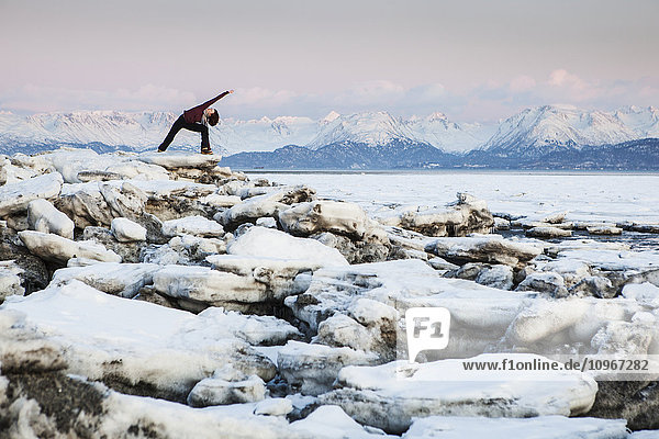 Woman practices yoga on an ice chunk on a beach in Homer  Southcentral Alaska