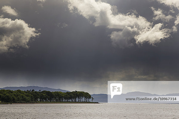 Bäume und Berge entlang der Küstenlinie unter Gewitterwolken; Otter Ferry  Schottland