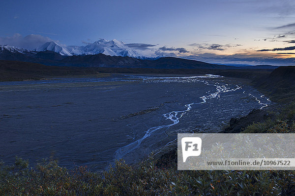 The Thorofare River winds down toward the McKinley River  while Denali towers in the twilight in Denali National Park & Preserve  Alaska  in autumn.
