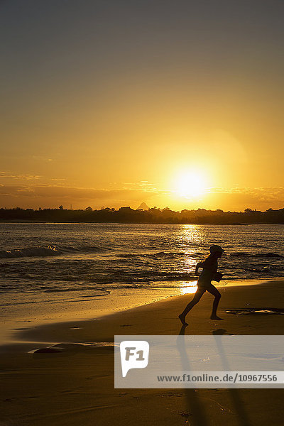 'Silhouette of a child running on a beach at sunset; Caloundra  Queensland  Australia'