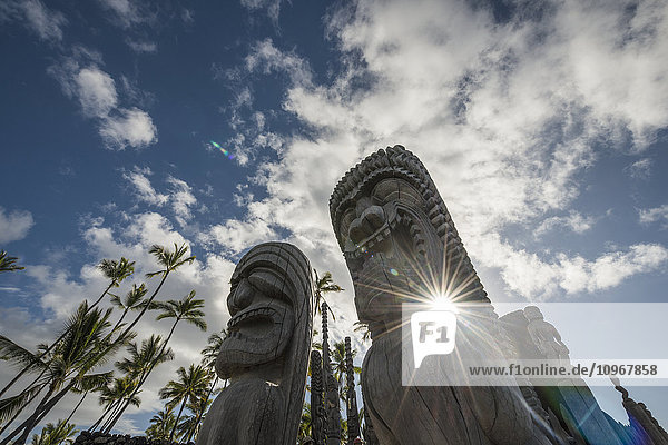 Nachmittagssonne scheint durch die Statuen im Puuhonua O Honaunau National Historic Park; Insel Hawaii  Hawaii  Vereinigte Staaten von Amerika'.