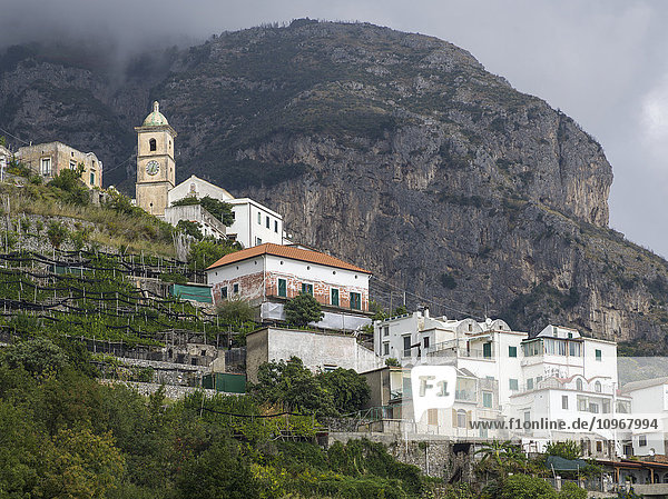 Häuser auf einem Hügel und ein großer Berg entlang der Amalfiküste; Amalfi  Italien'.