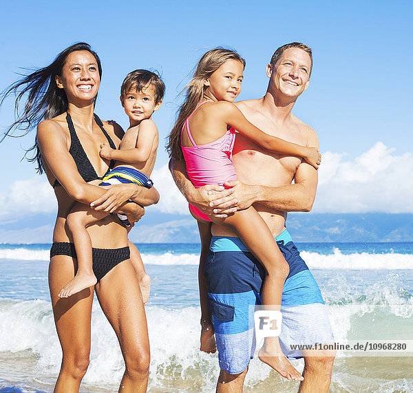 Happy Mixed Race Family of Four on Tropical Sunny Beach