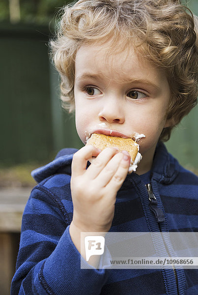 'Young boy eating a s'more outdoors and getting sticky; St. Albert  Alberta  Canada'